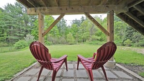 A covered outdoor seating area with two chairs and a view of a grassy landscape. - Visit us 3 minutes from Tanglewood music hall and Kripalu Yoga Center (Lenox)