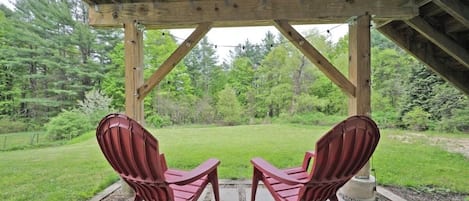Un espace extérieur abrité, aménagé avec deux chaises et offrant une vue sur un paysage verdoyant.