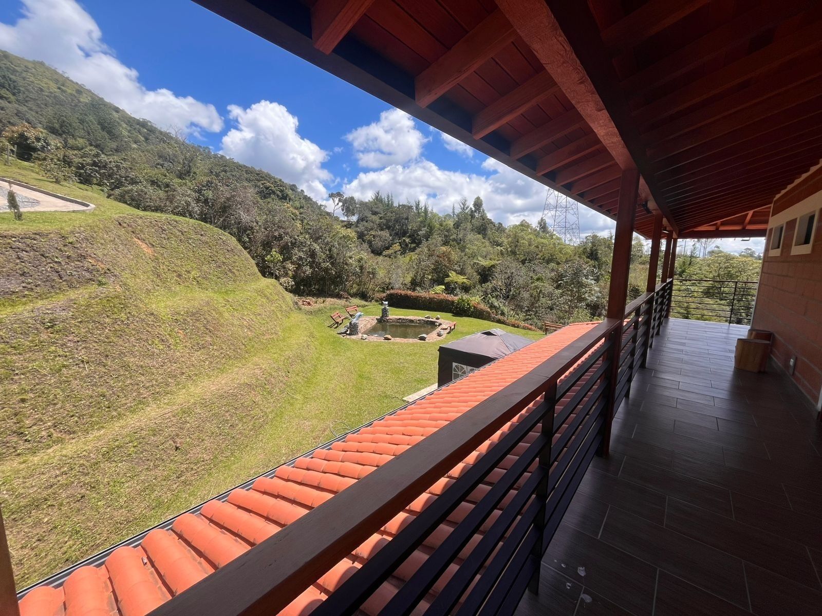 Ein Balkon mit Blick auf einen angelegten Garten und einen Teich.