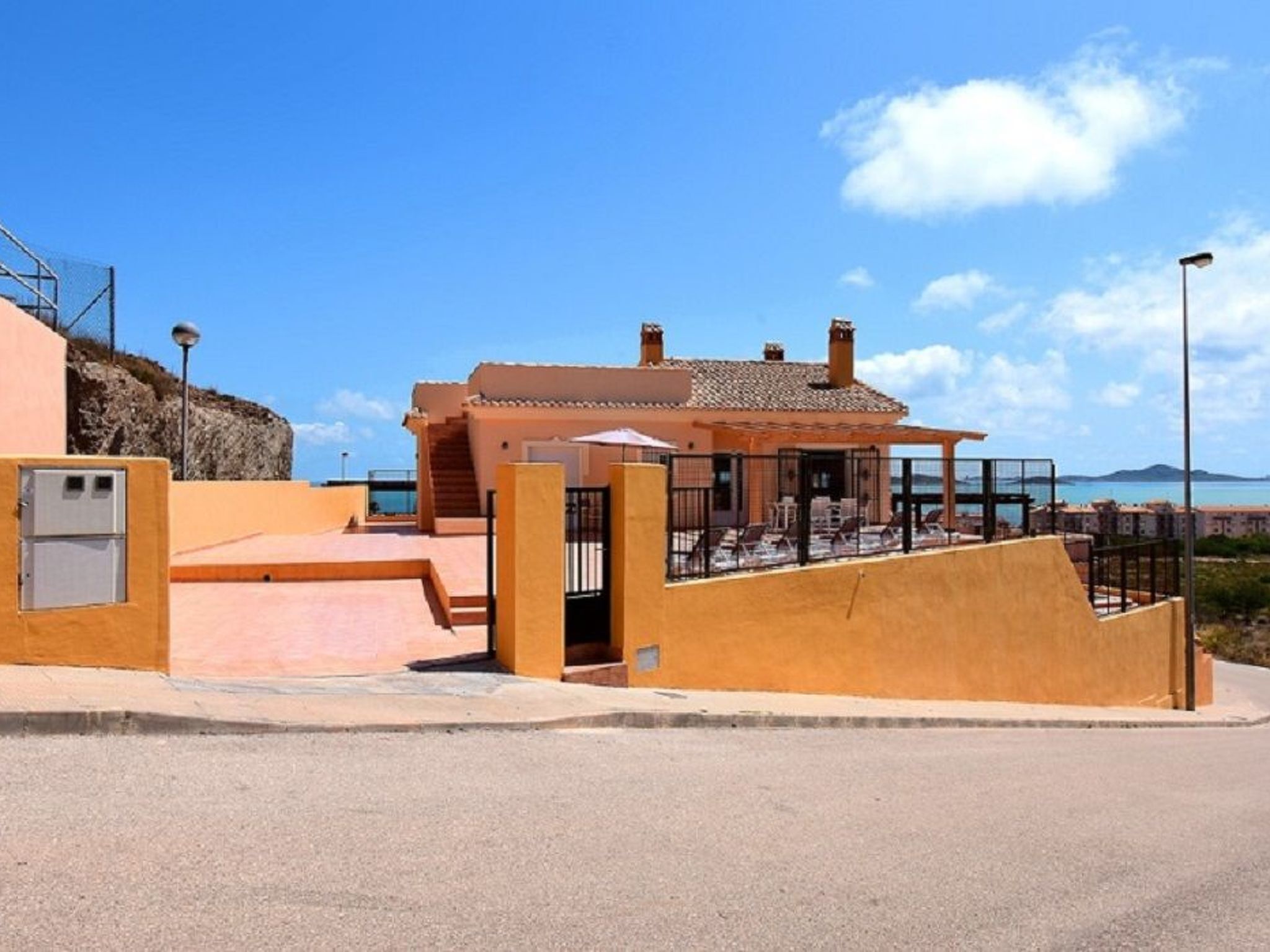 A coastal building with a patio area, a covered seating area, and a view of the sea.