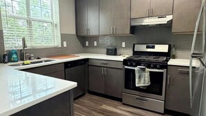 Eine moderne Küche mit dunklen Schränken, einem Edelstahl-Kühlschrank und einem eingebauten Backofen.