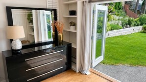 Quarto moderno com um console preto, um espelho grande e uma porta de vidro deslizante para um jardim.