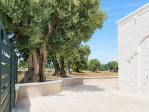 A paved entrance area with a white wall and a metal gate. - Tenuta Polignano - La Scuderia, a Rural Estate in Puglia.  Exposed Stone Arches (Puglia)