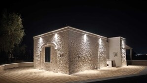 A stone building with a tiled roof and a small attached structure. - Tenuta Polignano - La Scuderia, a Rural Estate in Puglia.  Exposed Stone Arches (Puglia)