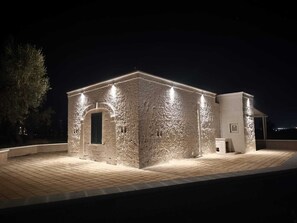 A stone building with a tiled roof and a small attached structure. - Tenuta Polignano - La Scuderia, a Rural Estate in Puglia.  Exposed Stone Arches (Puglia)