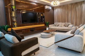 A modern living room with a flat-screen TV, sofas, a coffee table, and decorative items. - Cozy Keys Luxury Apartments (Abuja)