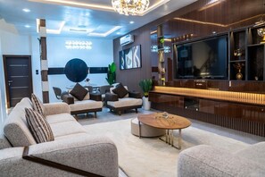A modern living room with a sofa set, a coffee table, a TV, and decorative items. - Cozy Keys Luxury Apartments (Abuja)