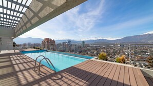 Piscina no terraço com vista para a cidade e montanhas.