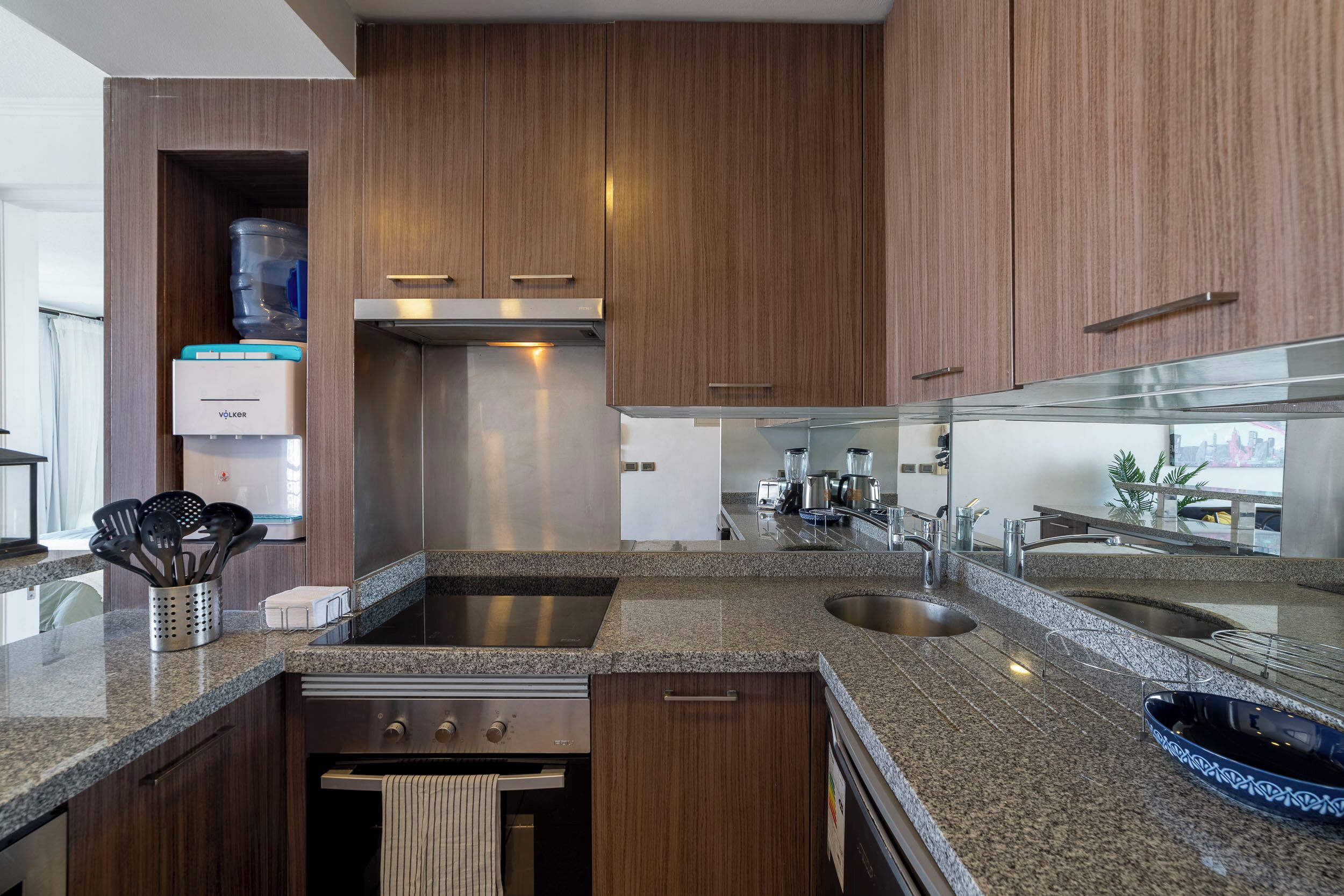 A modern kitchen with granite countertops, stainless steel appliances, and wooden cabinetry.