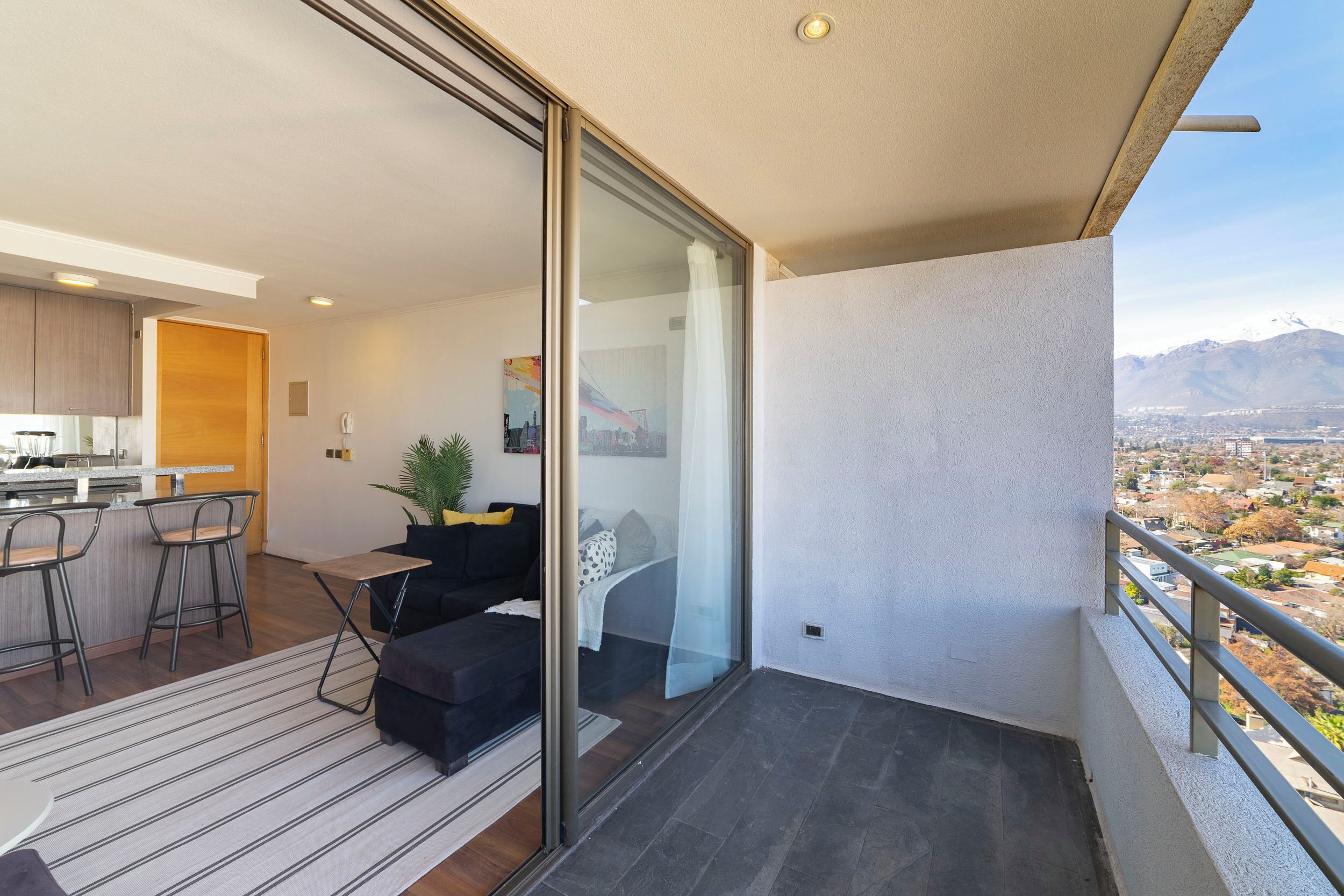 Eine moderne Wohnung mit Küche, Essbereich und einem Balkon mit Blick auf die Stadt.