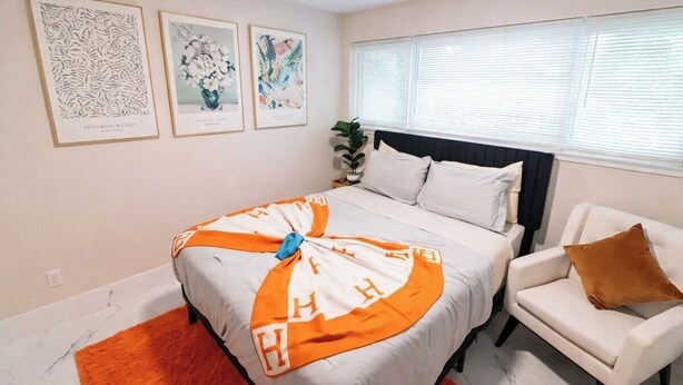 Una camera da letto con un letto, una sedia e opere d'arte appese al muro.