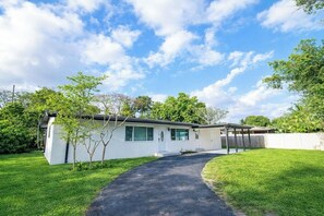 A modern single-story house with a paved driveway leading to a covered porch. - Luxury Pool Retreat • Near Hard Rock • Sleeps 10 (Fort Lauderdale)