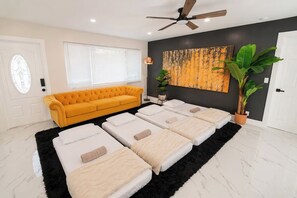 A room with a yellow sofa, massage tables, a ceiling fan, a large painting, and a potted plant. - Luxury Pool Retreat • Near Hard Rock • Sleeps 10 (Fort Lauderdale)