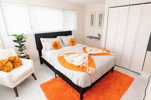 Une chambre à coucher avec un lit, une chaise, une plante et une armoire.