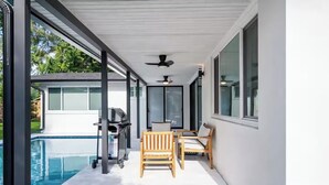 Un'area esterna coperta con piscina, barbecue e posti a sedere.