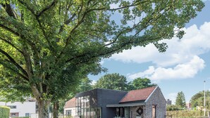 Ein modernes Haus mit einer Stein-Fassade, großen Fenstern und einer Terrassenfläche.
