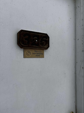A non-smoking sign on a white door with a brass plate above it. - Cozy 1-bedroom hotel room, Hamilton - #326 Taylor (Hamilton)