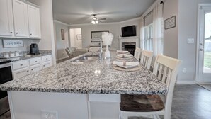 A kitchen with a granite countertop, white cabinets, a built-in oven, and a dining area with a white table and chairs. - Marvelous 4-bedroom house, 5 miles from the square in vibrant Athens (Athens)