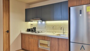 Eine moderne Küche mit Holzschränken, einem Edelstahlkühlschrank, einem Einbauofen und einem Spülbecken.