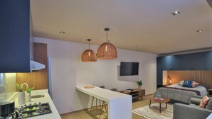 Ein modernes Wohnzimmer mit einer Couch, einem Couchtisch, einem Fernseher und einem Essbereich mit einem weißen Tisch und Stühlen.