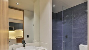 Ein modernes Badezimmer mit einem weißen Waschbecken, einer Glasdusche und einer Toilette.