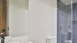 Ein modernes Badezimmer mit Waschbecken, Toilette und einer Dusche mit Glaswand.