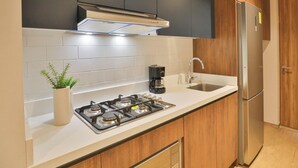 Eine moderne Küche mit Gasherd, Edelstahlkühlschrank und Holzschränken.