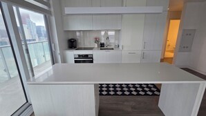 A modern kitchen with white cabinetry, a built-in oven, and a large window overlooking a cityscape.