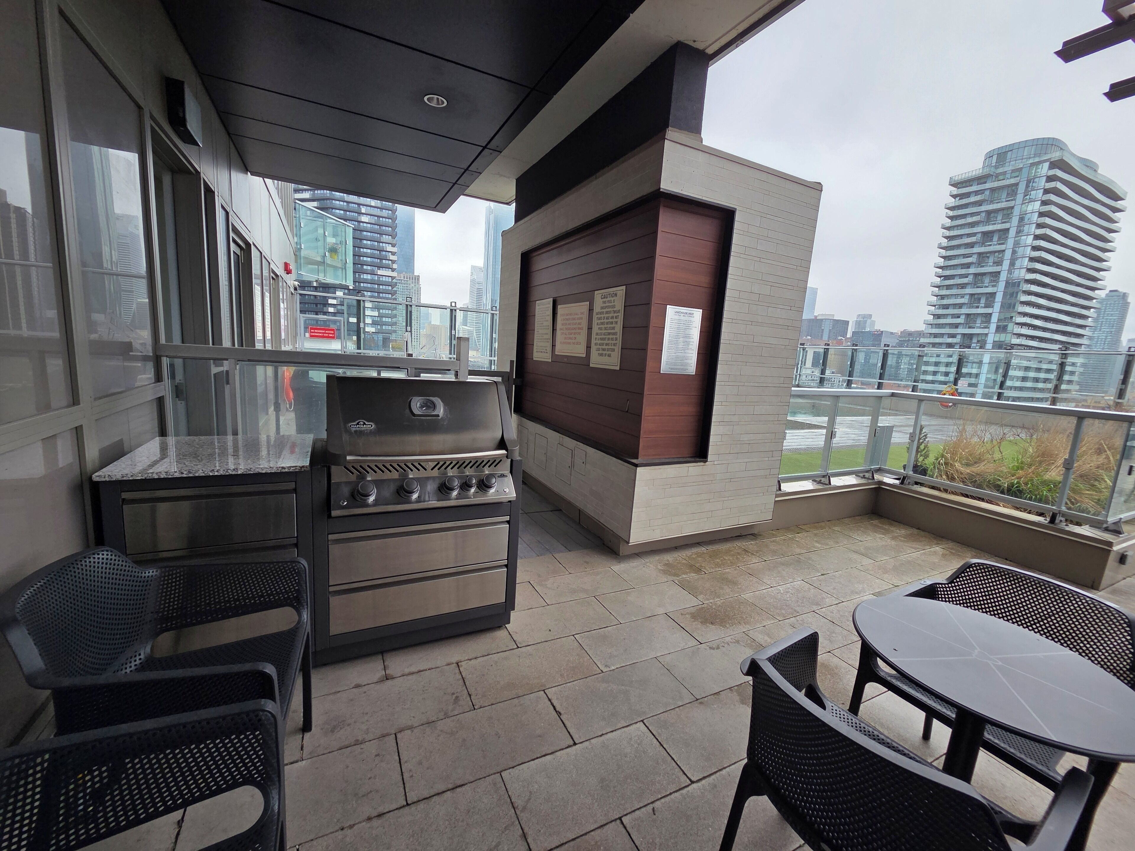 Balcón exterior con una parrilla, zona de estar y vistas a la ciudad.