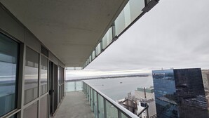 A balcony with a view of a river and a building with a glass facade.