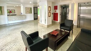 A spacious lobby with a marble floor, a reception desk, and a seating area with leather chairs and a coffee table. - Modern apartment in Meireles • Modern Apartment near Beira Mar (Fortaleza)