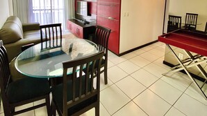 A modern living room with a glass dining table, a sofa, and a kitchen area with red cabinets. - Modern apartment in Meireles • Modern Apartment near Beira Mar (Fortaleza)