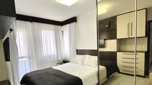 A bedroom with a bed, a bedside table, a mirror, and a wardrobe. - Modern apartment in Meireles • Modern Apartment near Beira Mar (Fortaleza)