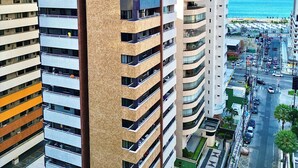 A high-rise building with multiple balconies, a view of the sea, and a busy street below. - Modern apartment in Meireles • Modern Apartment near Beira Mar (Fortaleza)