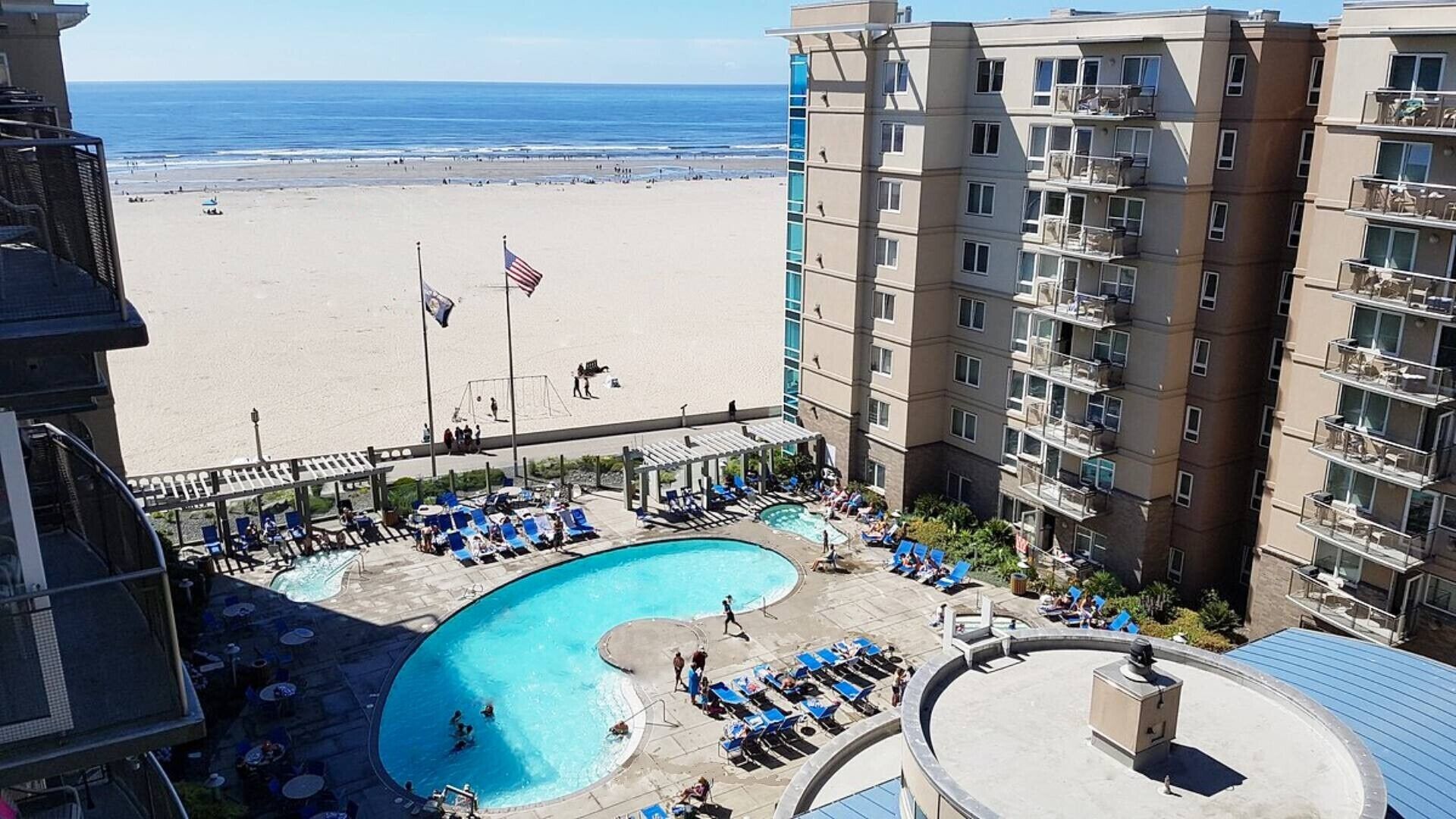 Ein Hotel mit Poolbereich, Blick auf den Strand und einer Flagge.