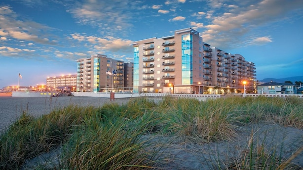 A beachfront hotel with multiple floors, balconies, and a view of the ocean.
