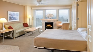 Una habitación de hotel con cama, sofá, una mesita, chimenea y ventana con persianas.