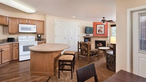 A kitchen with wooden cabinets, a microwave, an oven, and a dining area with a fireplace.