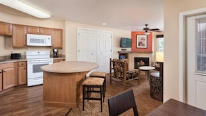 A kitchen with wooden cabinets, a microwave, an oven, and a dining area with a fireplace.