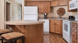 A kitchen with wooden cabinets, a white refrigerator, a microwave, a coffee maker, and a stove.