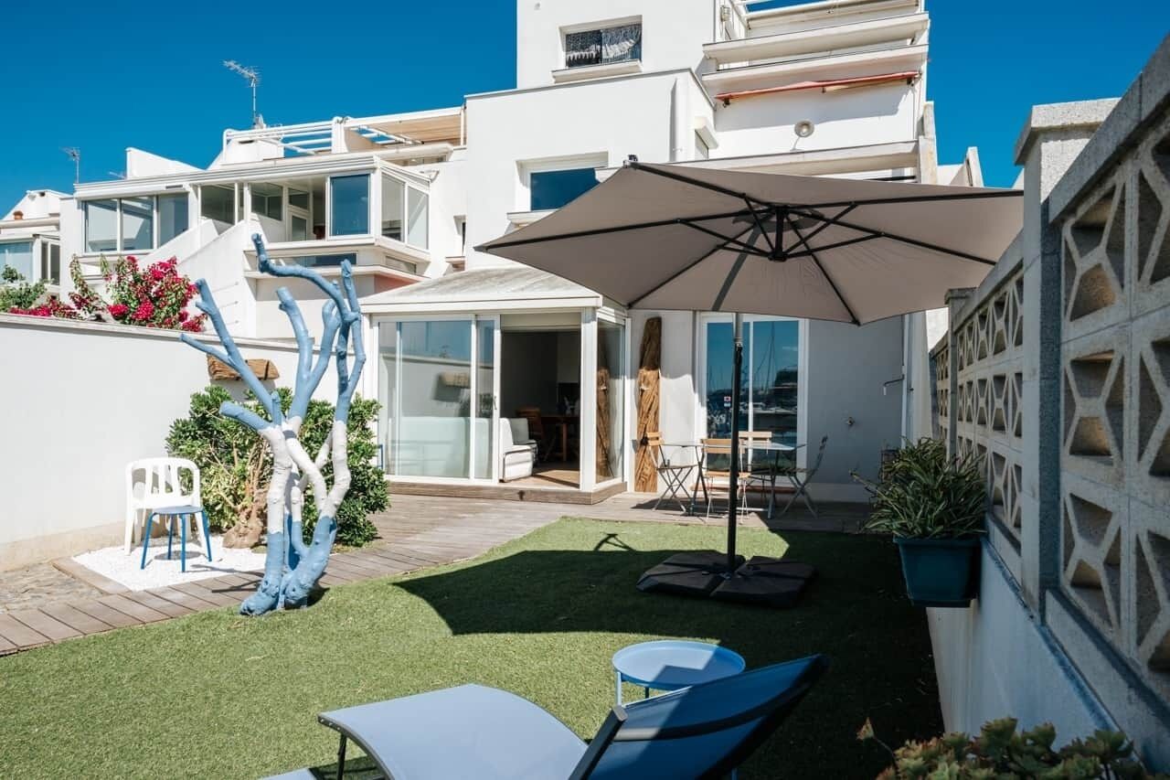 Une villa moderne dotée d’un patio, de mobilier d’extérieur et d’un grand parasol.