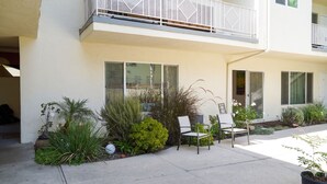 En moderne bygning med balkon, store vinduer og udendørs siddepladser.