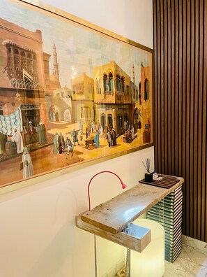 A wall with a large historical painting depicting a traditional scene, a wooden bench with books, and a modern light fixture. - Residential neighborhood in Nervi, just a stone's throw from the sea (Genova)