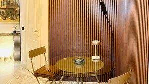 Ein Zimmer mit einem runden Glastisch, zwei Stühlen, einer Lampe und einer Wand aus Holzlatten.