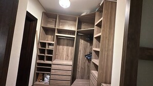 A walk-in closet with multiple shelves and drawers, a hanging rod, and a shoe rack.