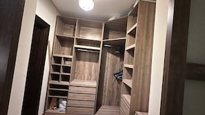Un dressing avec de nombreuses étagères et tiroirs, une tringle à vêtements et un porte-chaussures.