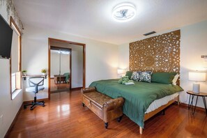 A bedroom with a bed, a desk, a chair, and a decorative wall panel. - Beautiful 4-bedroom hotel suites with AC in Deltona Garden House (Deltona)