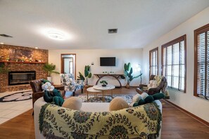 A living room with a fireplace, a sofa, a coffee table, and a TV mounted on the wall.