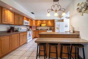 A kitchen with wooden cabinets, a granite countertop, and a bar stool area.