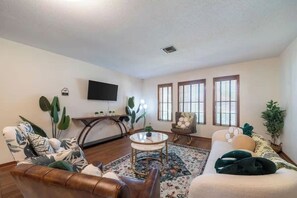A living room with a sofa, a coffee table, and a TV mounted on the wall.